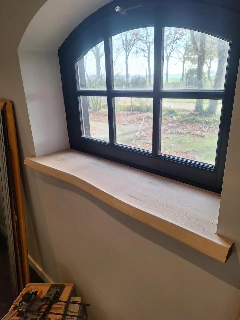 Appui de fenêtre en chêne sous une fenêtre cintrée à petits bois