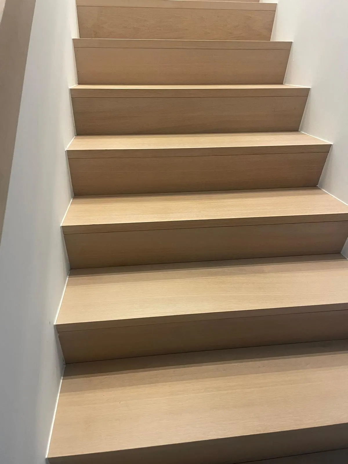 Escalier droit habillé de marches en chêne massif entre deux murs blancs