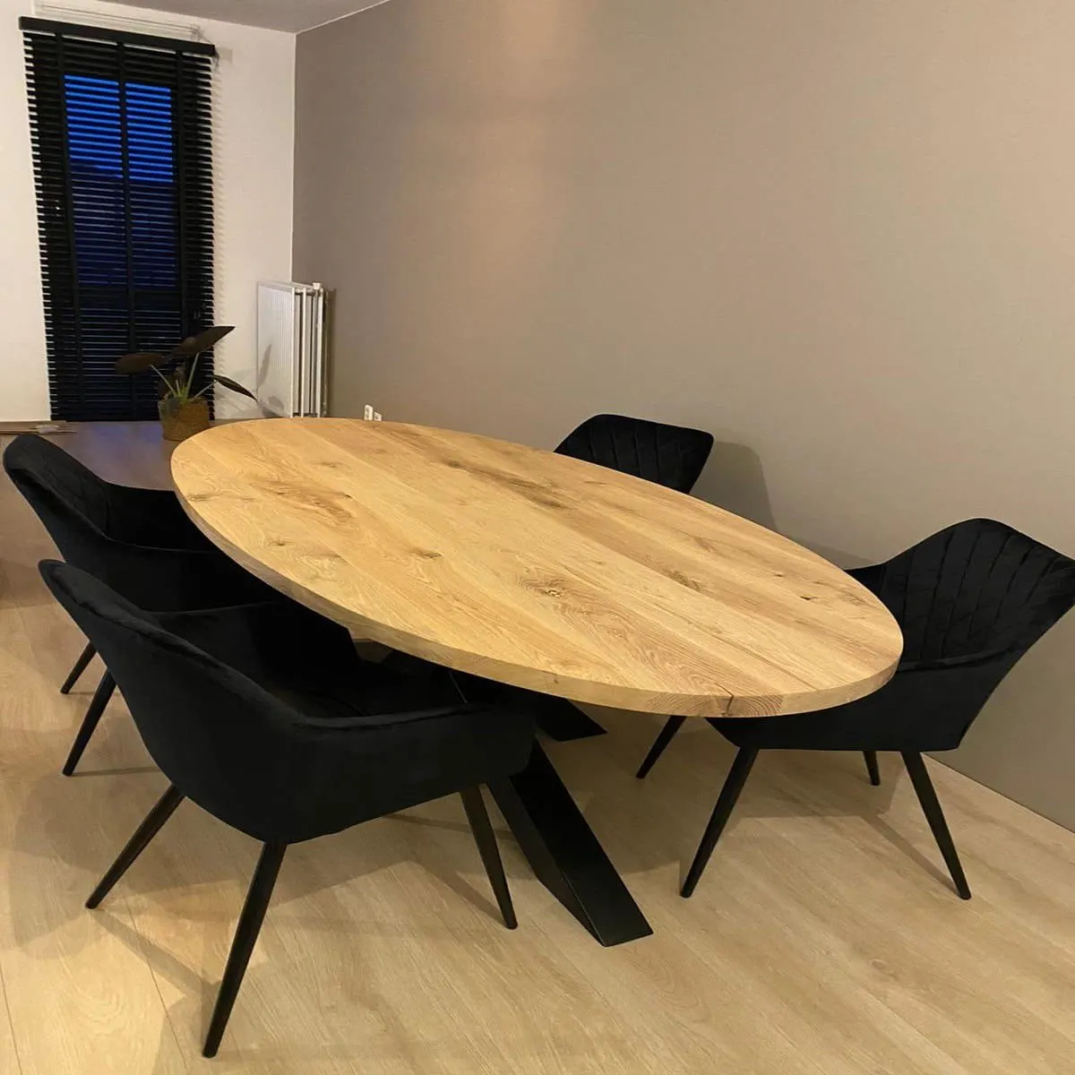 Plateau de table ovale en chêne massif dans une salle à manger, avec des chaises noires