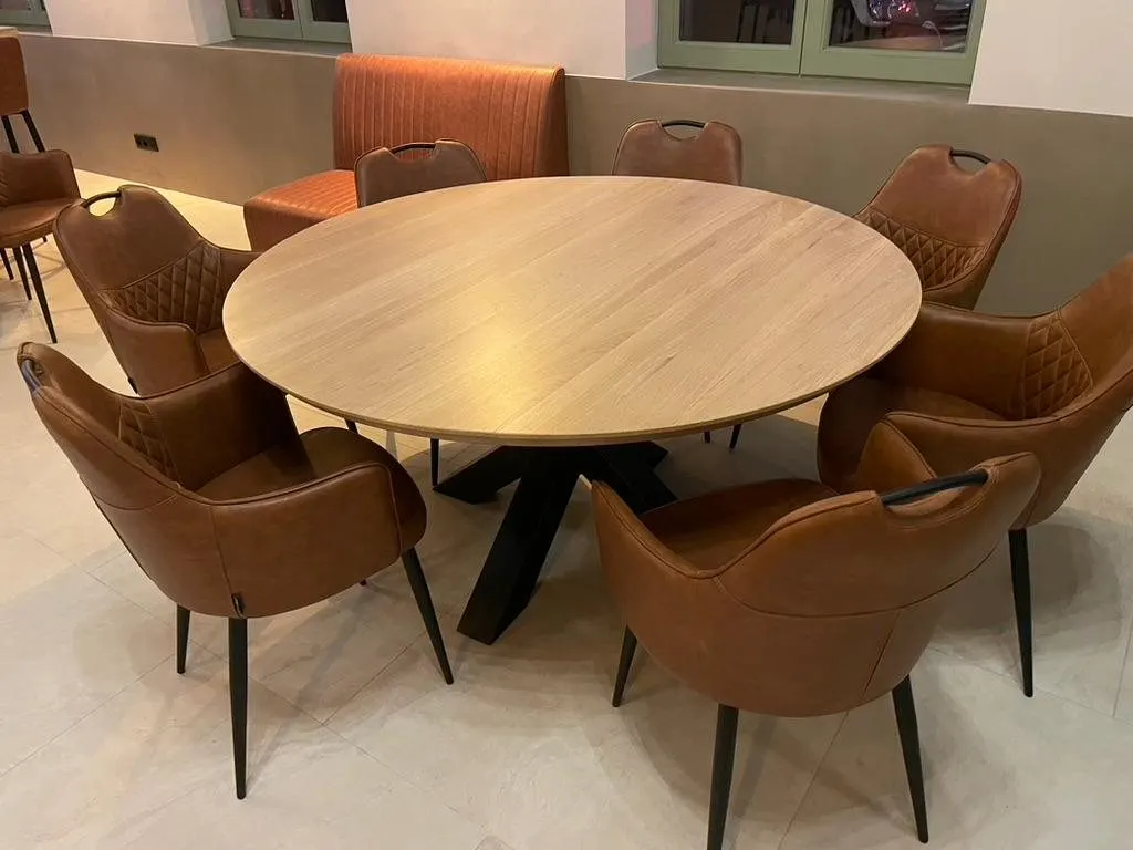 Plateau de table rond en chêne massif entouré de chaises en cuir cognac